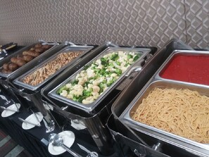 Ein Buffet mit verschiedenen Speisen, darunter Frikadellen, Nüsse, Brokkoli, Blumenkohl und Pasta.