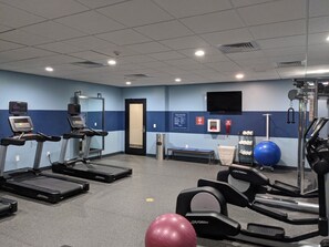Uma academia com esteiras, bicicleta ergométrica e bolas de exercício.