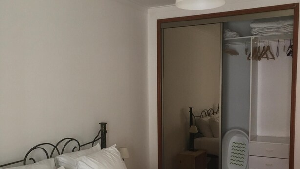 A neatly made bed with white linens, a hanging white lamp, and a wooden headboard. - FAMILY APARTMENT LISBON - TAGUSPARK (São Marcos)