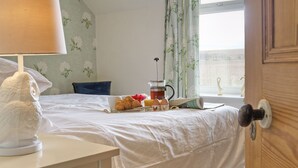 A neatly made bed with a breakfast tray, a coffee maker, and decorative items.