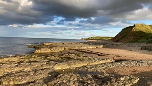 A coastal landscape with rocky terrain and a sandy beach.
