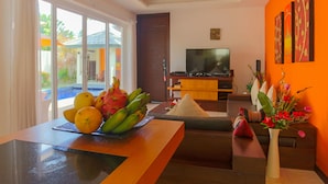 Ein modernes Wohnzimmer mit Fernseher, Obstschale und Blumenvase.
