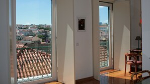 Een kamer met een grote schuifglazen deur die uitkomt op een balkon met een betegeld dak.