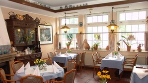 A dining area with multiple tables set for meals, wooden chairs, and a large cabinet with glass doors.