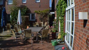 A patio area with a brick floor, outdoor furniture, and potted plants.