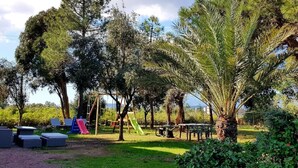 A playground with slides and swings surrounded by trees and grass. - Beautiful villa in park with trees 10 minutes walk from the beach (Porto-Vecchio)