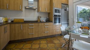Una cucina moderna con mobili in legno, un tavolo da pranzo in vetro e un pavimento effetto pietra.