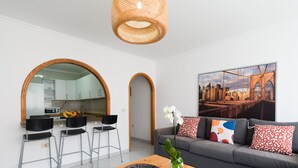 A modern living room with a grey sofa, a wooden coffee table, and a large cityscape painting.