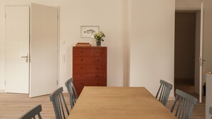 A dining area with a wooden table and chairs, a red dresser, and a framed picture on the wall. - Apartment Gut Üselitz on Rügen - 1. First floor left (Poseritz)