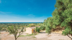 A small building with a tiled roof, surrounded by sparse vegetation and a clear view of the distant landscape. - Nice home in Badesi OT with house sea view (Badesi OT)
