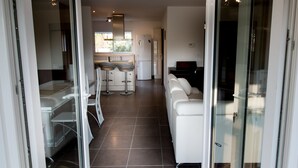 Una cocina moderna con una isla central, un comedor con sillas y un sofá blanco en la sala de estar.