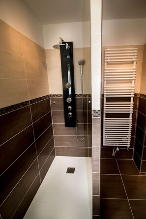 Un baño moderno con ducha acristalada, bañera blanca y toallero empotrado.