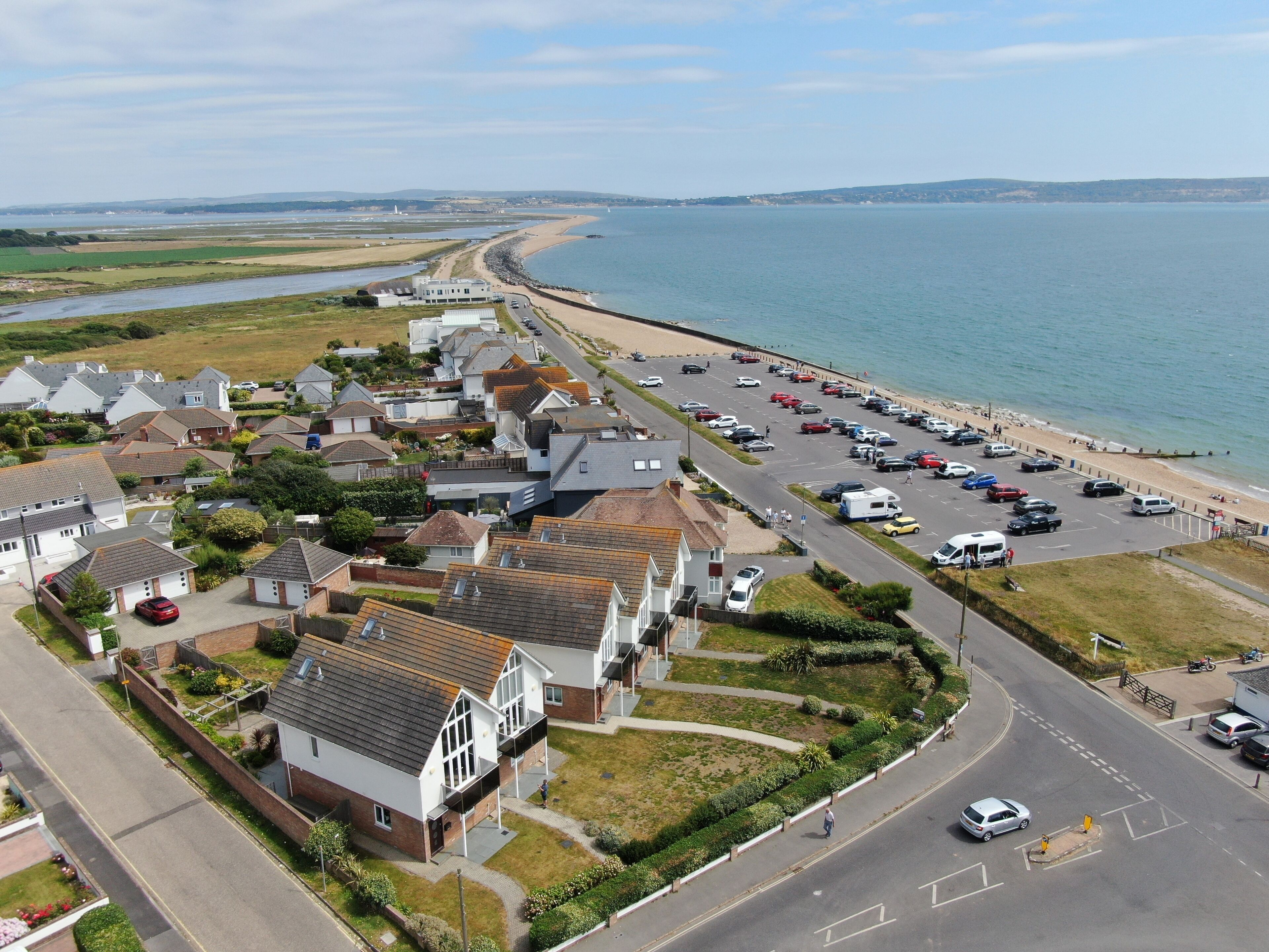 A coastal residential area with houses, a beach, and a parking lot.