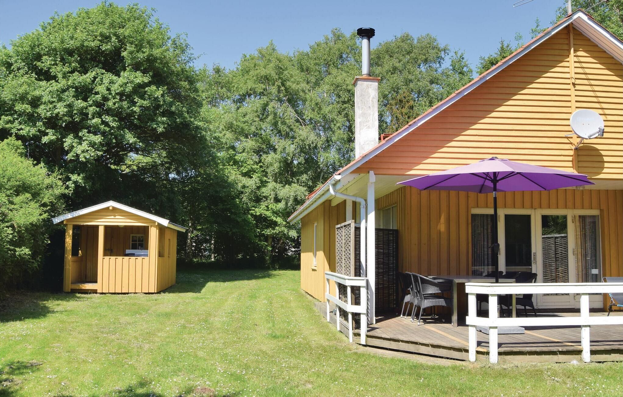 Une cabane en bois jaune, dotée d’un porche et d’une petite dépendance attenante.
