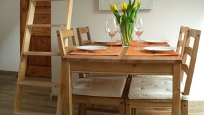 Une table à manger en bois avec des chaises, une échelle en bois et une suspension lumineuse dans une pièce dotée d’un plafond en pente et d’un mur en marbre.