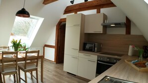 Une cuisine compacte équipée d’un four à micro-ondes, d’un four traditionnel et d’un petit coin repas avec une table et des chaises.
