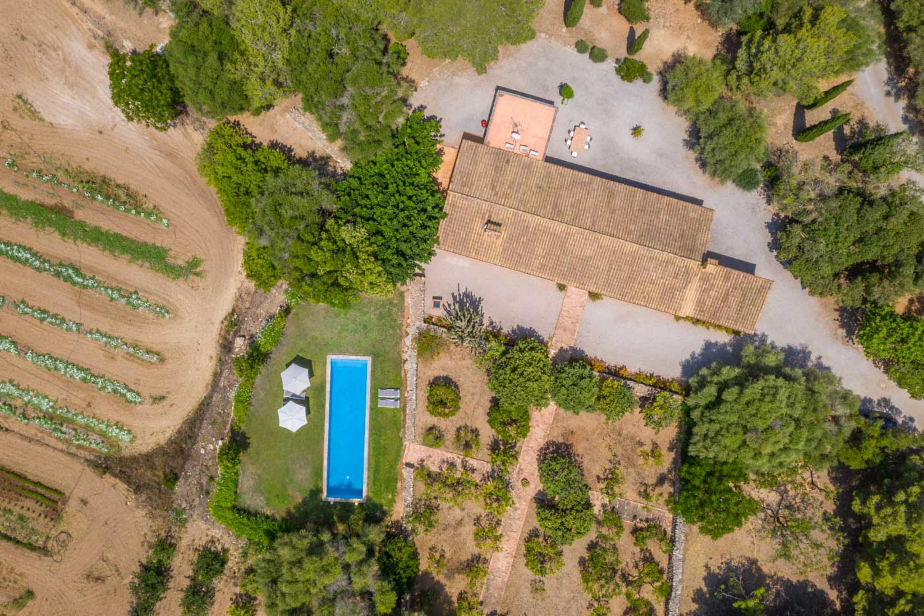 Ein Luftbild eines Anwesens mit einem großen Gebäude, einem Swimmingpool und umliegenden Grünflächen.