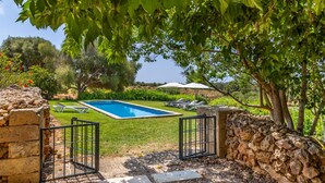 A swimming pool with a stone wall and a gate, surrounded by a well-maintained lawn and trees. - 784524 Ses Cases, Spain (Manacor)