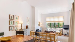 A spacious living area with a wooden dining table, cushioned chairs, a sofa, and a TV stand. - 784524 Ses Cases, Spain (Manacor)
