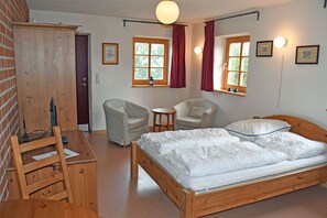 A room with a wooden bed, two chairs, a small table, and a wardrobe.