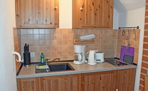 A kitchen with wooden cabinets, a sink, a coffee maker, a toaster, and a knife block.