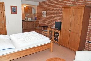 A room with a bed, wooden furniture, a television, and a brick wall.