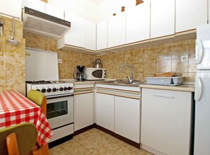 A compact kitchen with white cabinets, a stove, a microwave, and a sink. - Holiday apartment mit Terrasse und Klimaanlage (Ližnjan)