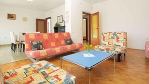 Un salon comprenant un canapé, un fauteuil à motifs, une table basse et un coin repas avec des chaises et une table.