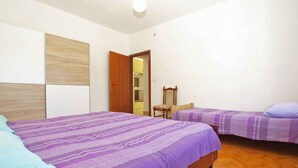 Une chambre avec deux lits, des têtes de lit en bois, une armoire et un miroir.