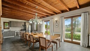 A spacious kitchen with modern appliances, a dining area with a large wooden table and chairs, and large sliding glass doors leading to a garden. - 780533 Finca s'hort de conies (Manacor)