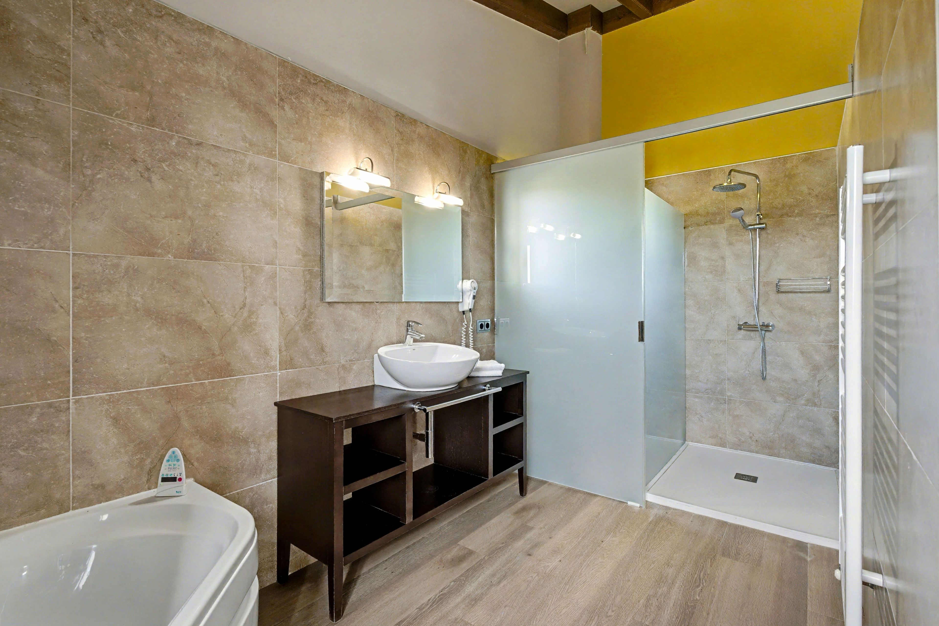 A modern bathroom with a bathtub, a sink, and a glass-enclosed shower.