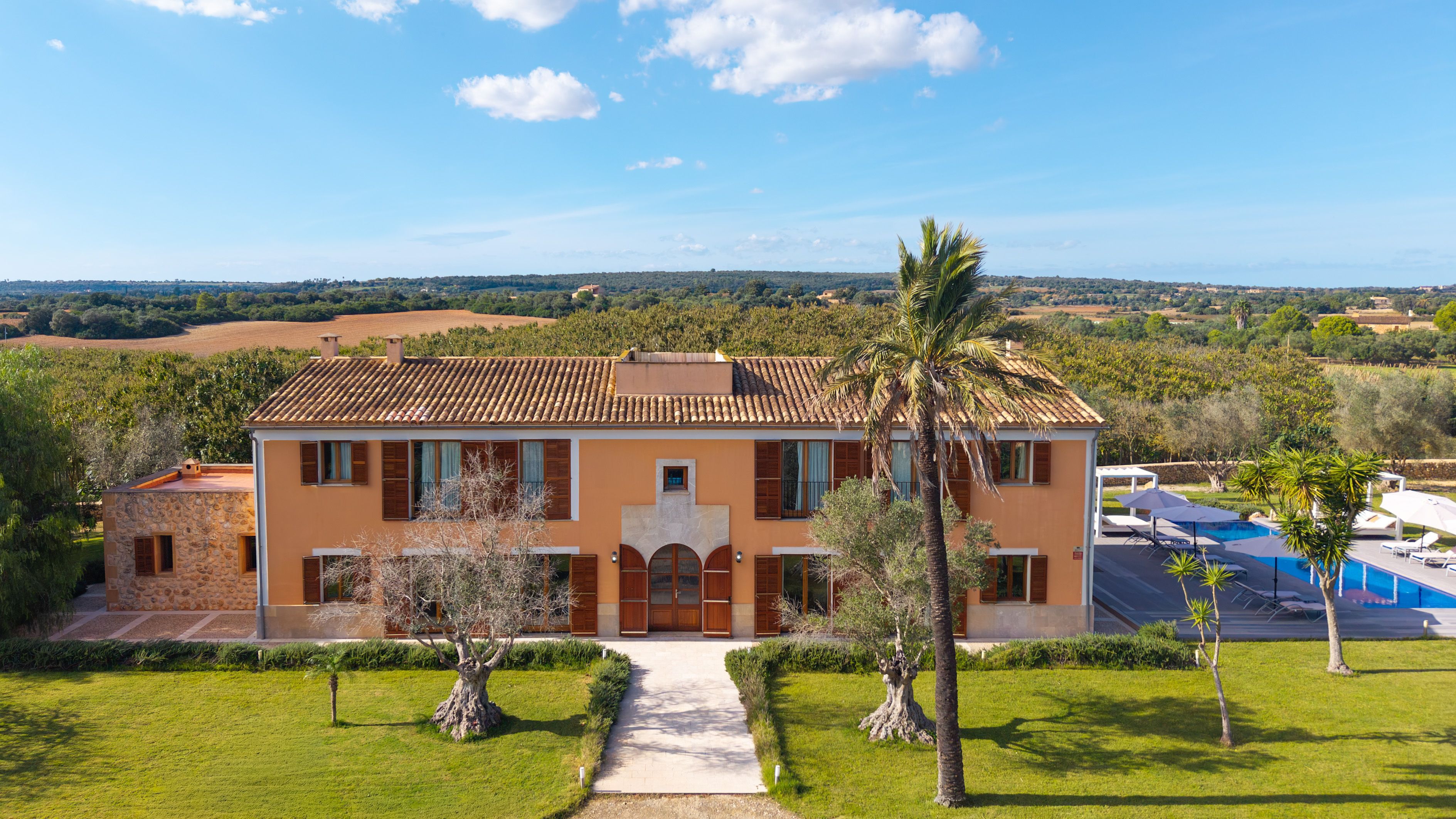 A two-story house with a tiled roof, a front entrance, and a swimming pool.