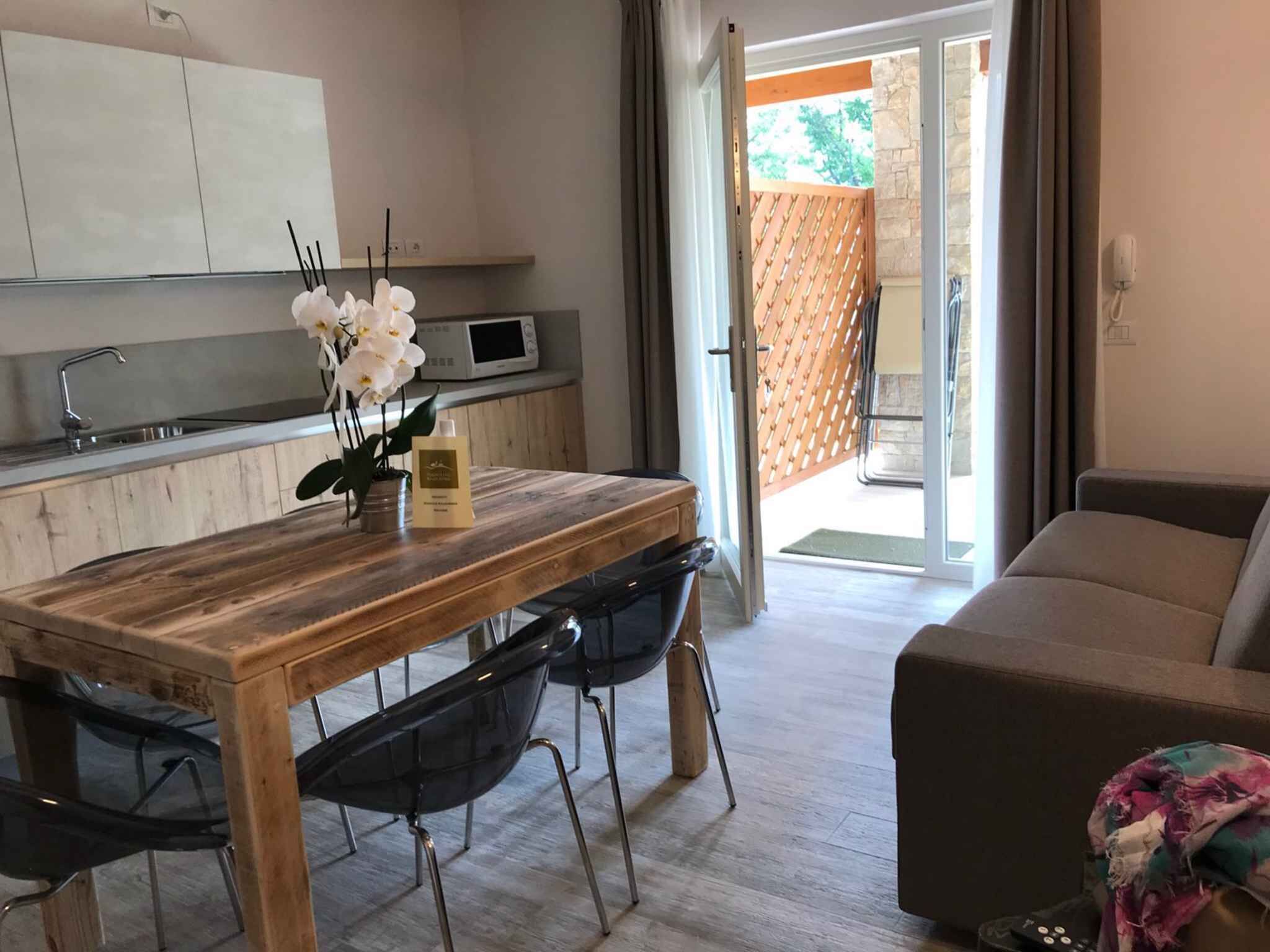 Una cocina moderna con una mesa de madera, sillas negras y una orquídea en maceta.