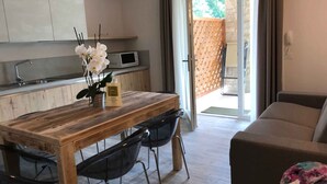 A modern kitchen with a wooden table, black chairs, and a potted orchid. - Holiday apartment mit Terrasse (Tignale)