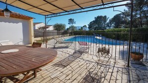 Un espacio al aire libre techado con piscina, una mesa de madera y una valla de metal.