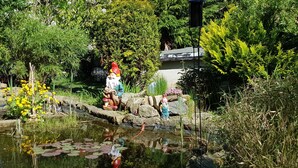 A garden with a pond, rocks, and statues of gnomes. - Apartment Sandra Mattaj (Blankenburg (Harz))