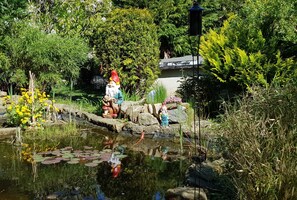 A garden with a pond, rocks, and statues of gnomes. - Apartment Sandra Mattaj (Blankenburg (Harz))