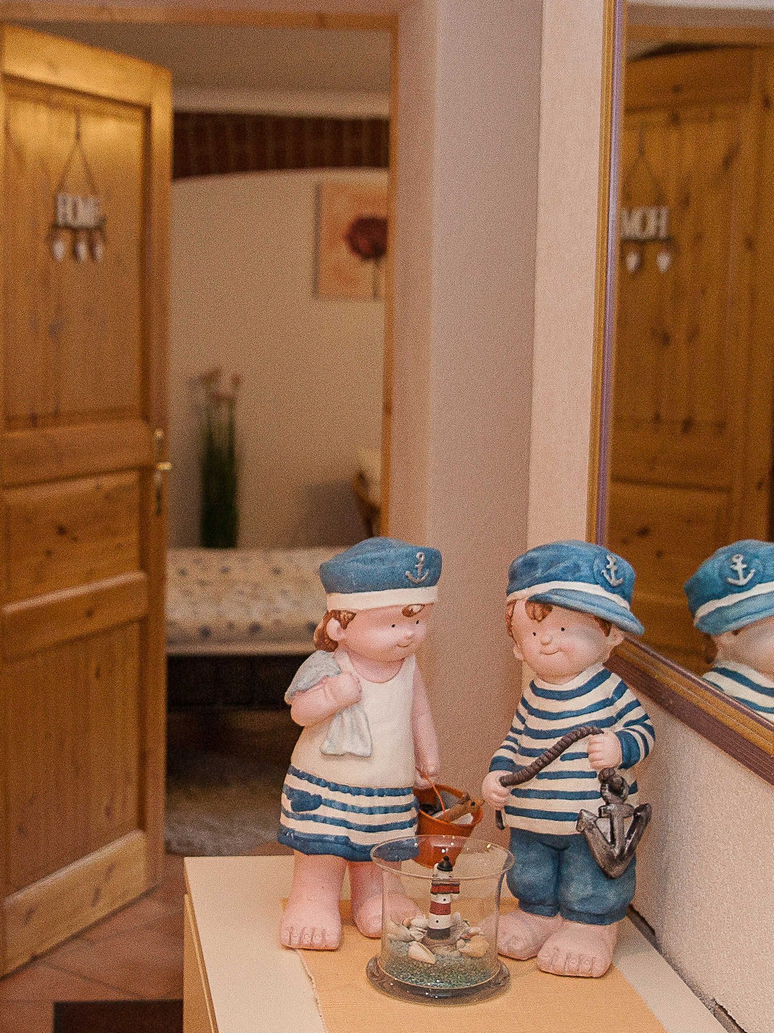 A doll in a room with a bed and a mirror.