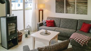 A cozy living room with a sofa, a small table, a fireplace, and a view of houses outside. - Gorgeous home in Breege/Juliusruh (Breege/Juliusruh)