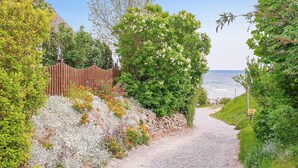 A gravel path leading to a beach, surrounded by lush greenery and flowering plants. - Gorgeous home in Breege/Juliusruh (Breege/Juliusruh)