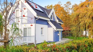 A two-story house with a blue exterior and a sloped roof, surrounded by autumn foliage. - Gorgeous home in Breege/Juliusruh (Breege/Juliusruh)