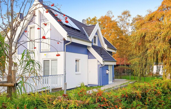 Et tosset hus med blå facade og et skråt tag, omgivet af efterårsblade.