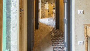 Un pasillo con piso a cuadros, paredes de piedra y vigas de madera.