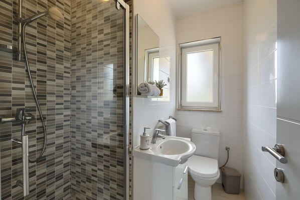 A modern bathroom with a glass-enclosed shower, a white sink, and a toilet.