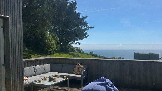 Un bain à remous sur une terrasse en bois, avec vue sur l’océan.