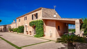 A stone building with a tiled roof, a covered porch, and a well-maintained lawn.