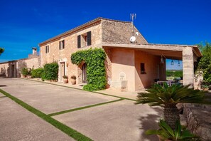 Un edificio in pietra con tetto in tegole, un portico coperto e un prato ben curato.