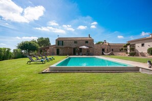 Un'ampia casa con piscina, prato verde e amaca.