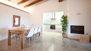 A spacious dining area with a wooden table and chairs, a kitchen with modern appliances, and a fireplace. - 44287 Finca Rústica Sa Pleta - 44287 Finca Rústica Sa Pleta (Manacor)