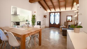 A spacious living area with a wooden dining table, white chairs, a sofa, and a potted plant.